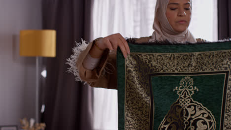 Muslimische-Frau-Mit-Hijab-Zu-Hause-Legt-Gebetsmatte-Auf-Etage-3